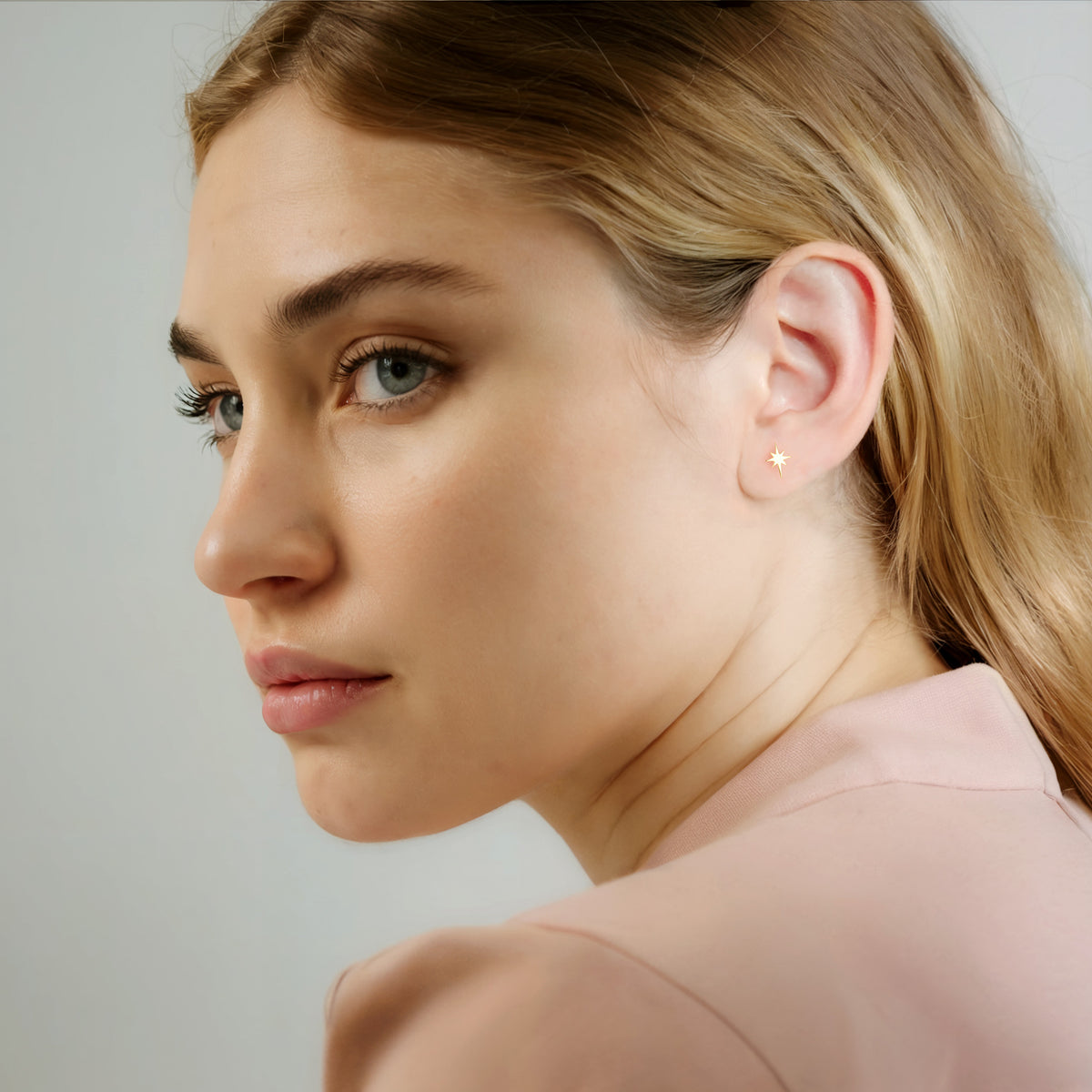 Model styled with small compass star earrings for a subtle celestial look