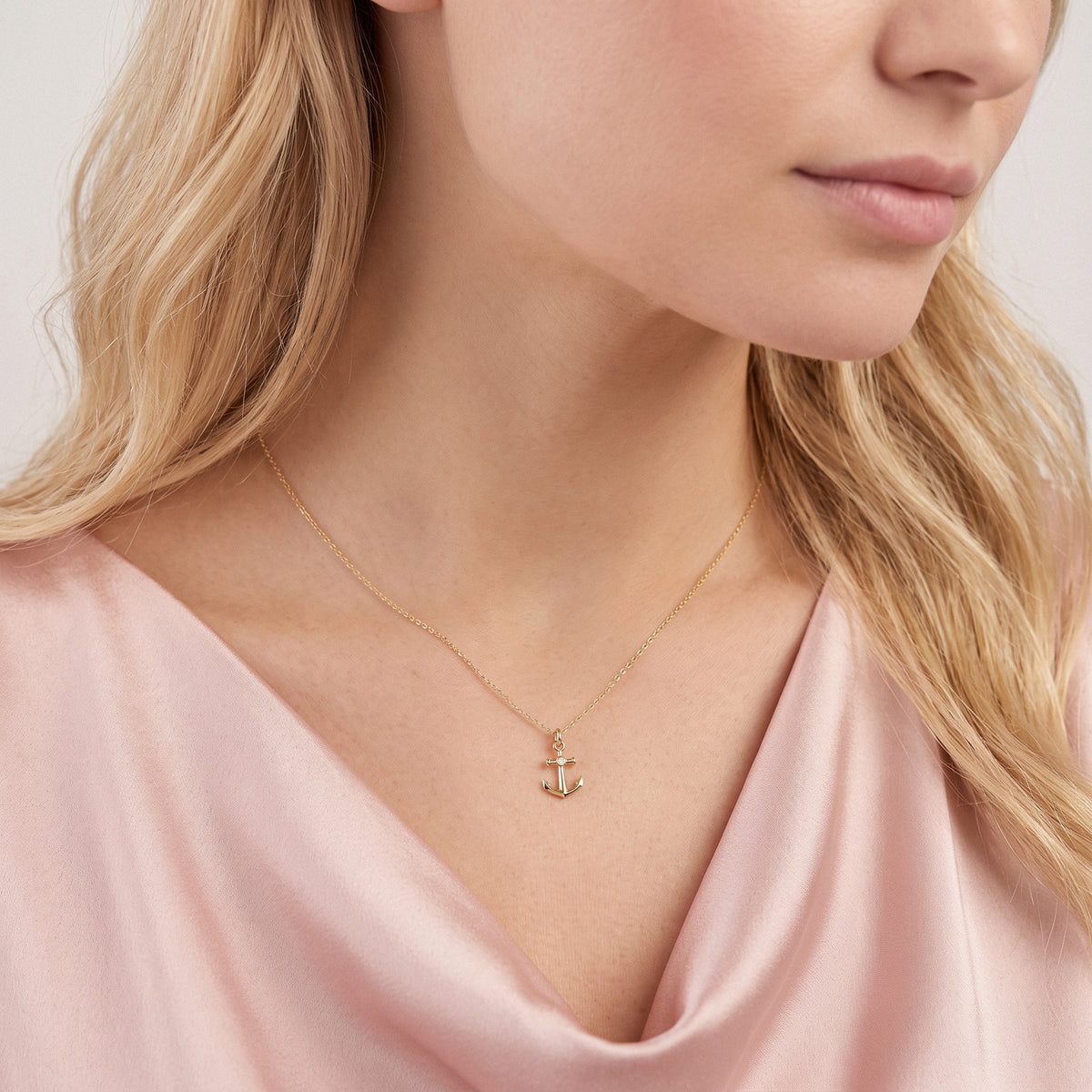 Anchor charm photographed close against a draped pink neckline