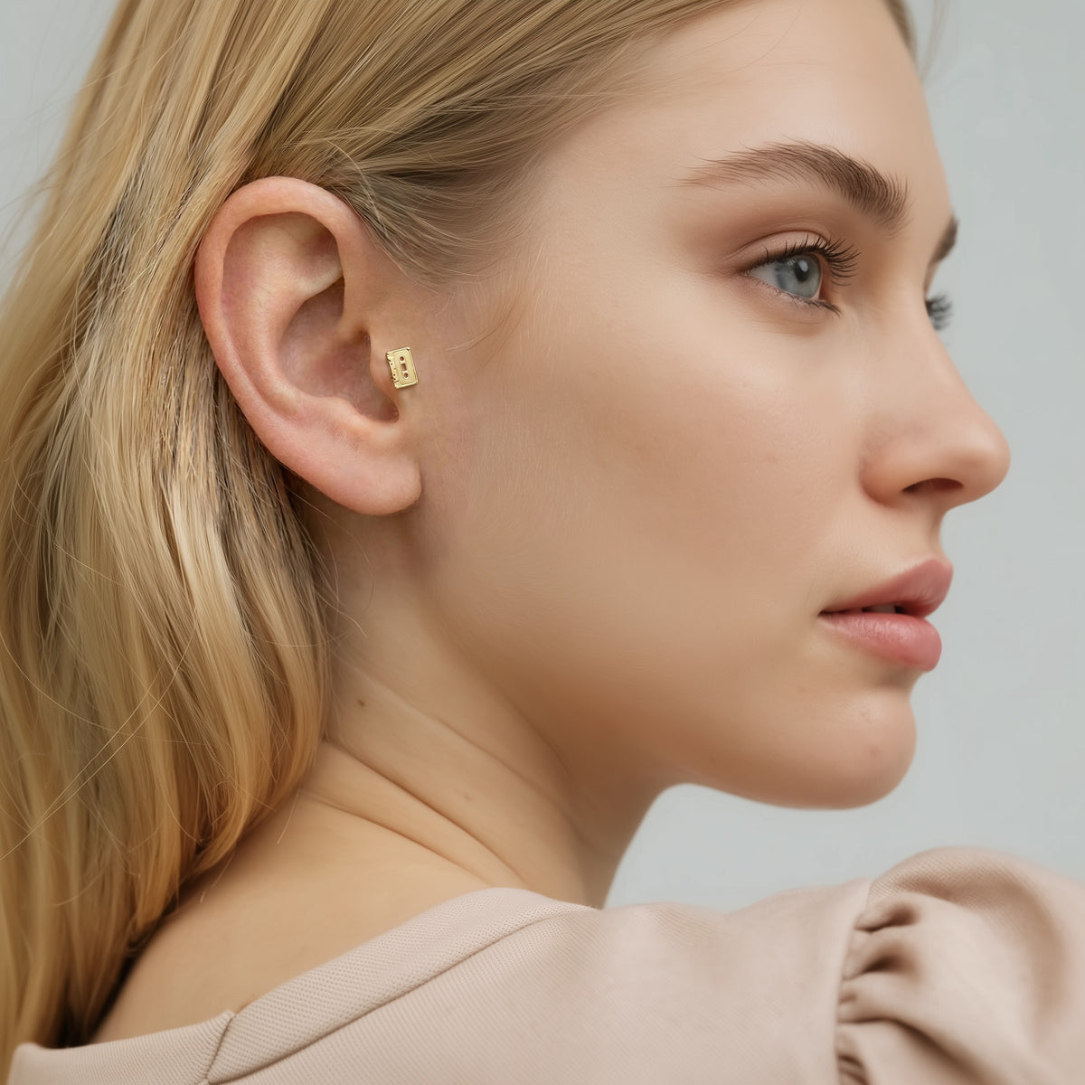 Model wears the miniature cassette flatback in a playful stack inspired by vintage music culture.