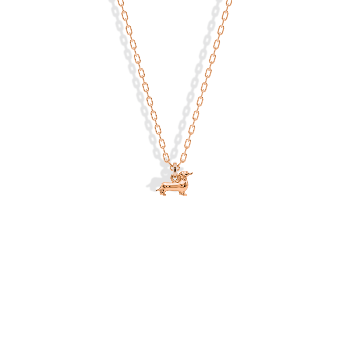Rose gold warms the dachshund’s elongated outline from muzzle to curled tail