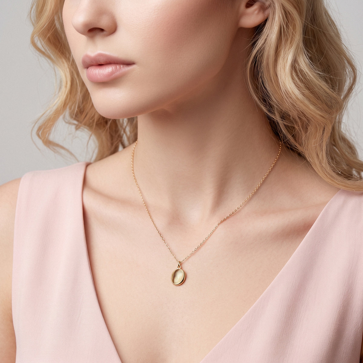 Fingerprint oval necklace worn with a pink off-shoulder top