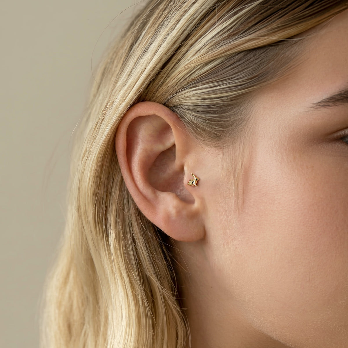 Tight ear crop showing the geometric bunny piercing at true scale beside a minimal cartilage stack.