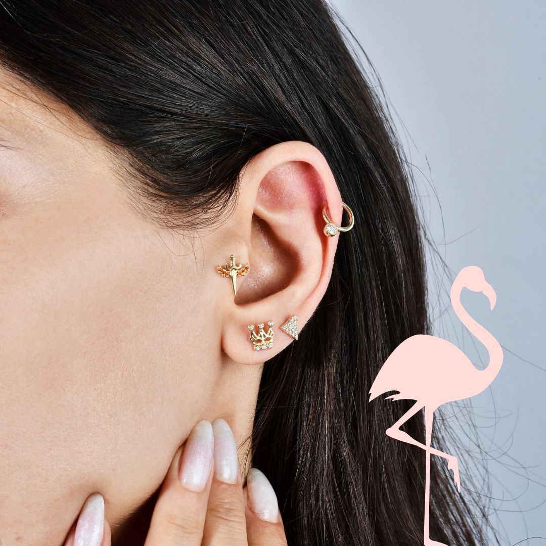 A woman's ear styled with the largest gold piercing collection, featuring multiple hoops, studs, and chains.