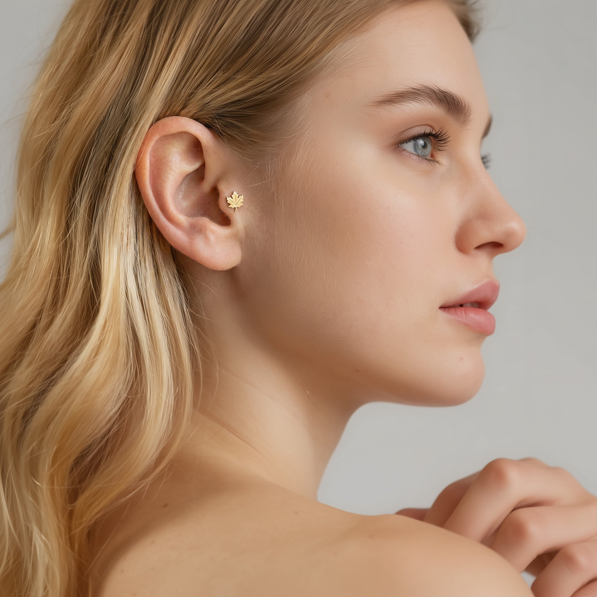 Model styling lets the small maple leaf flatback add a subtle botanical note to a clean ear composition.