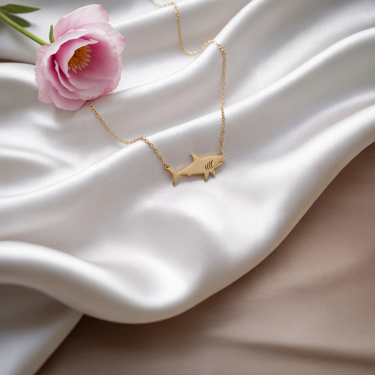 Ocean predator silhouette placed on white silk beside a pale pink peony