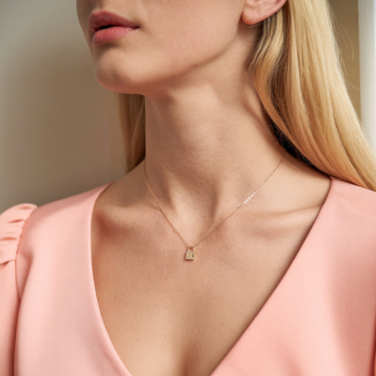 Close view of the stone set lock pendant against a peach silk neckline