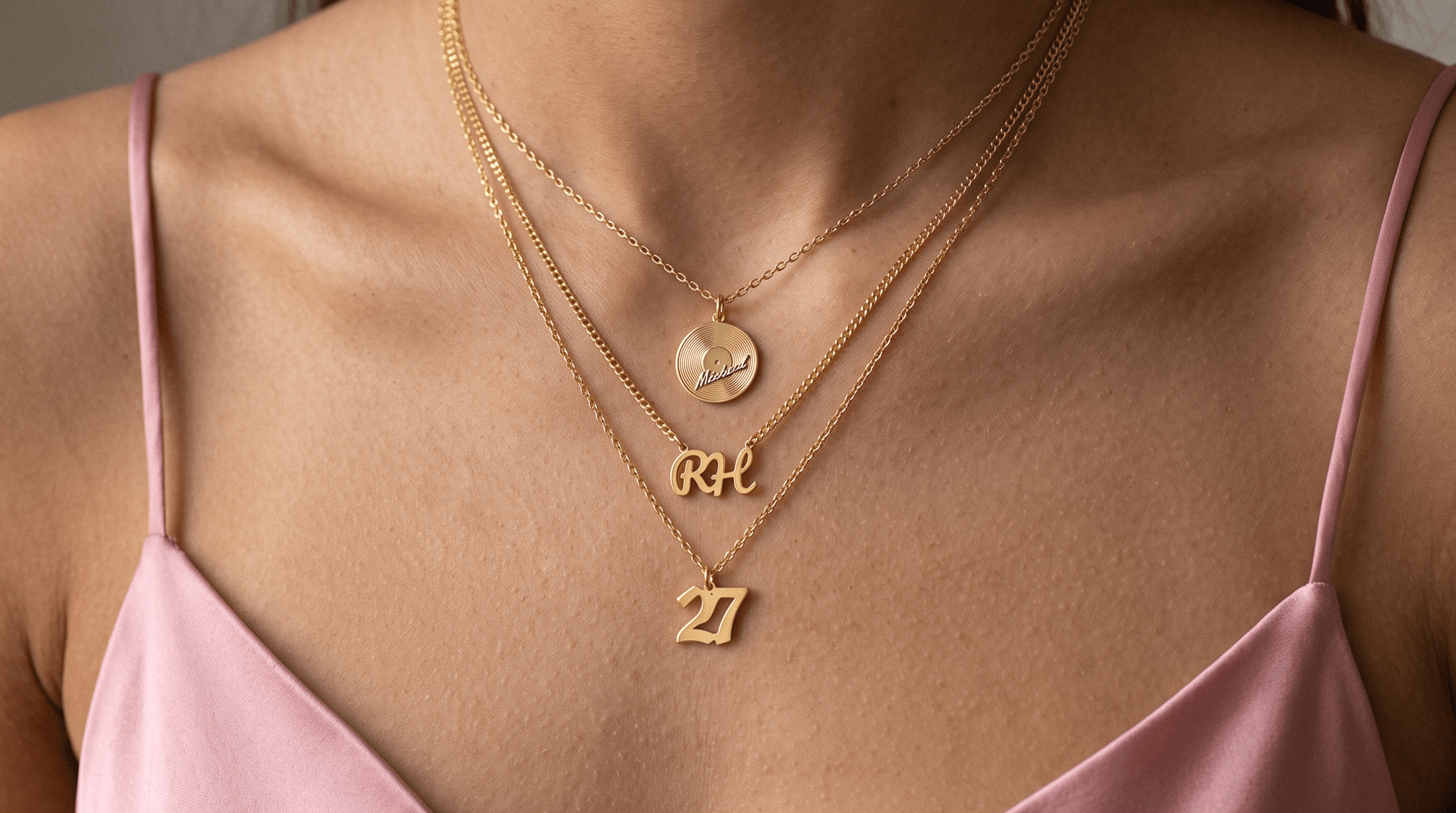 Personalized 14K gold initial pendant necklace and name necklace layered on a neutral linen surface
