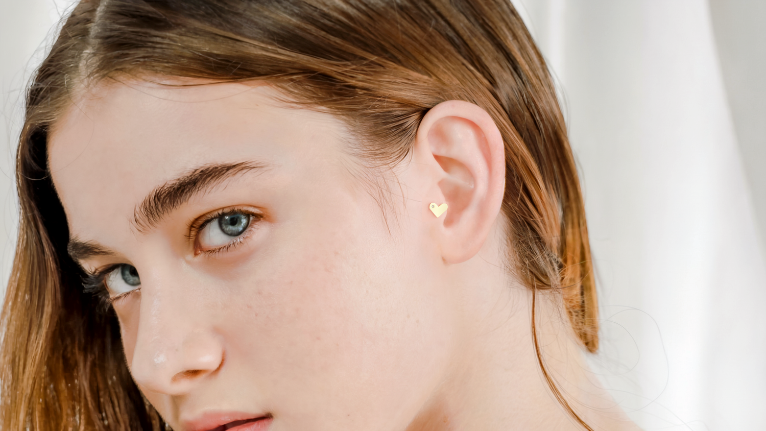 Tragus piercing with 14K gold hoop and diamond stud
