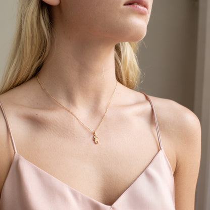 Close crop of the seahorse charm on a model in a blush strap dress