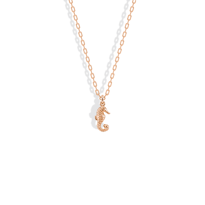 Seahorse charm in 14K rose gold, warm metal picking out the ridged back