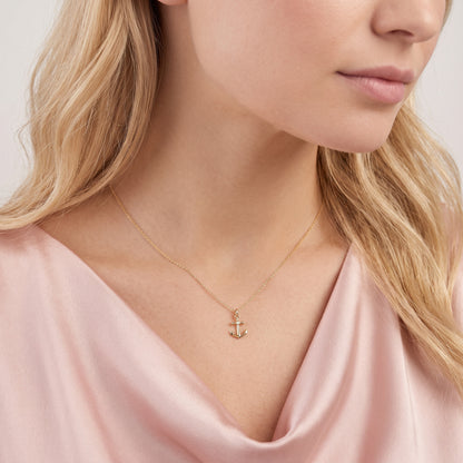 Anchor charm photographed close against a draped pink neckline