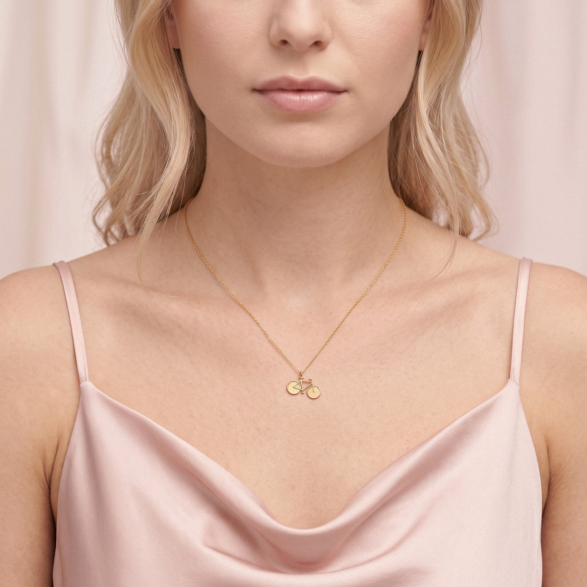 Tight crop of the bicycle charm lying on satin, wheels level with the neckline