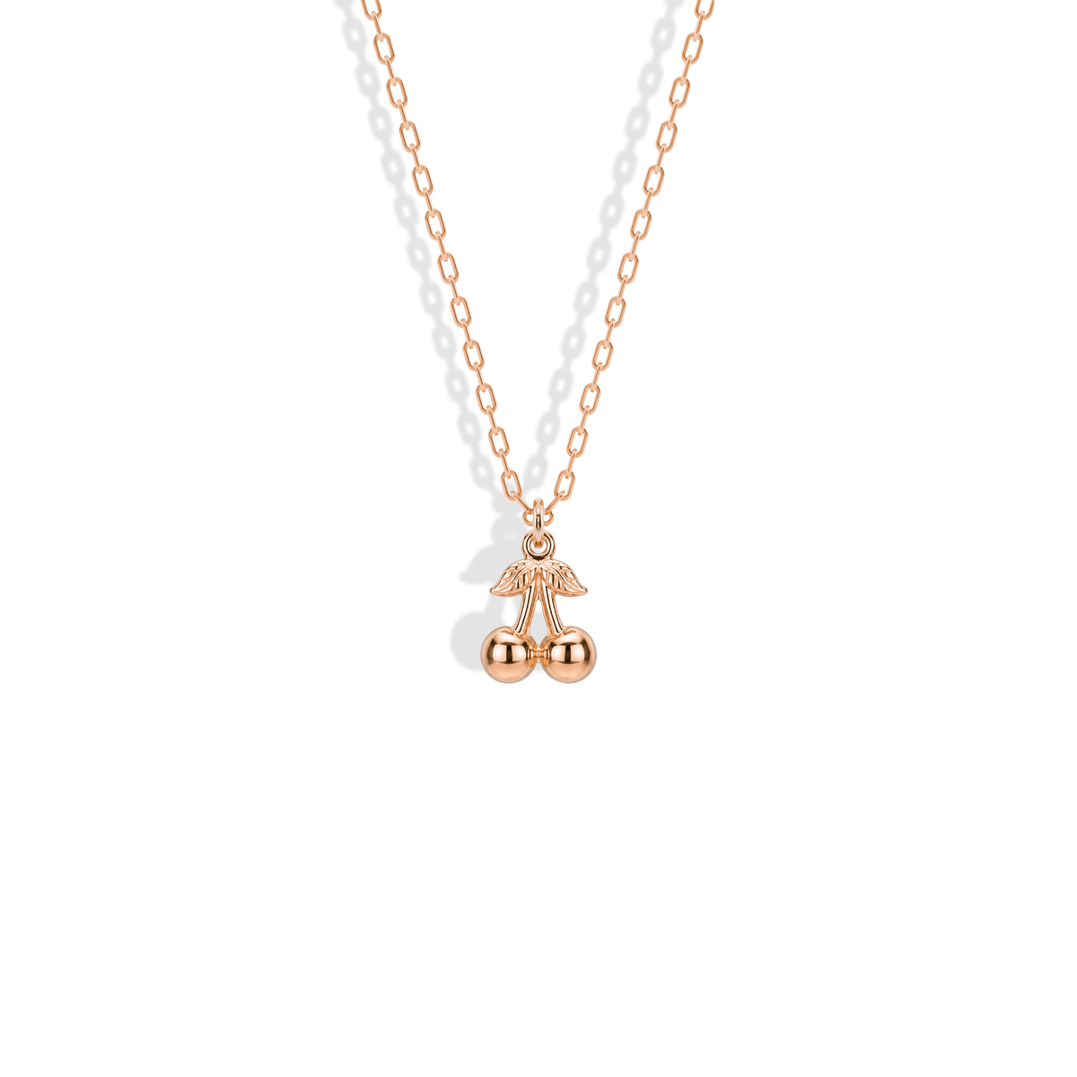 Rose gold cherry pendant, with warm pink metal highlighting the rounded fruit and textured stem