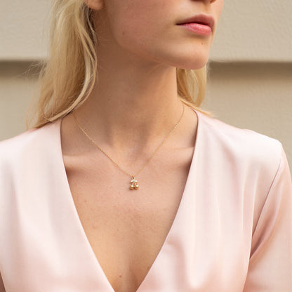 Model in a deep pink V-neck wearing the gold cherry charm at the centre of the neckline