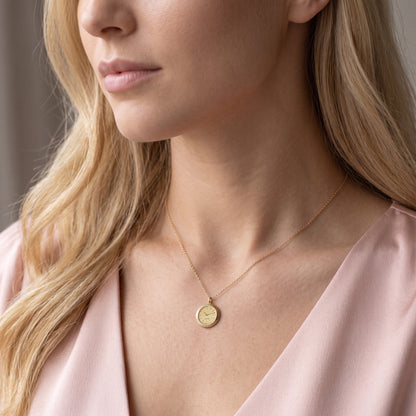 Model in a pink wrap top wearing the engraved watch face necklace
