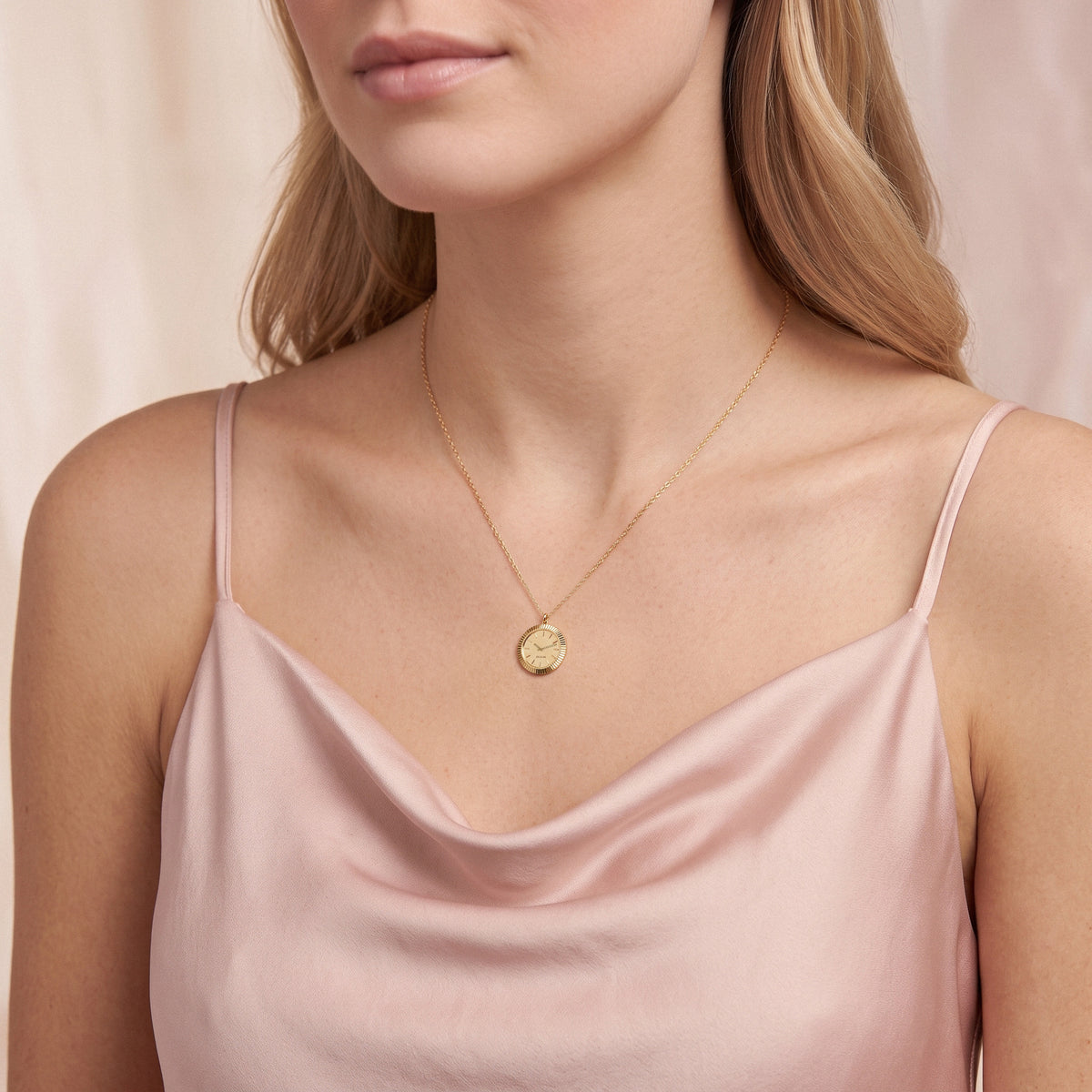 Watch dial pendant resting on a satin camisole neckline, dial markings visible