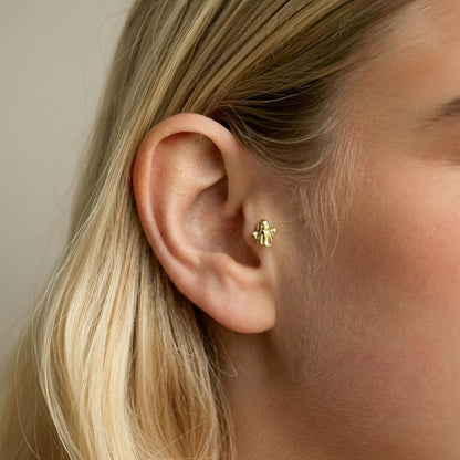 Close ear styling of the tiny ghost flatback piercing, showing its playful face and compact scale.