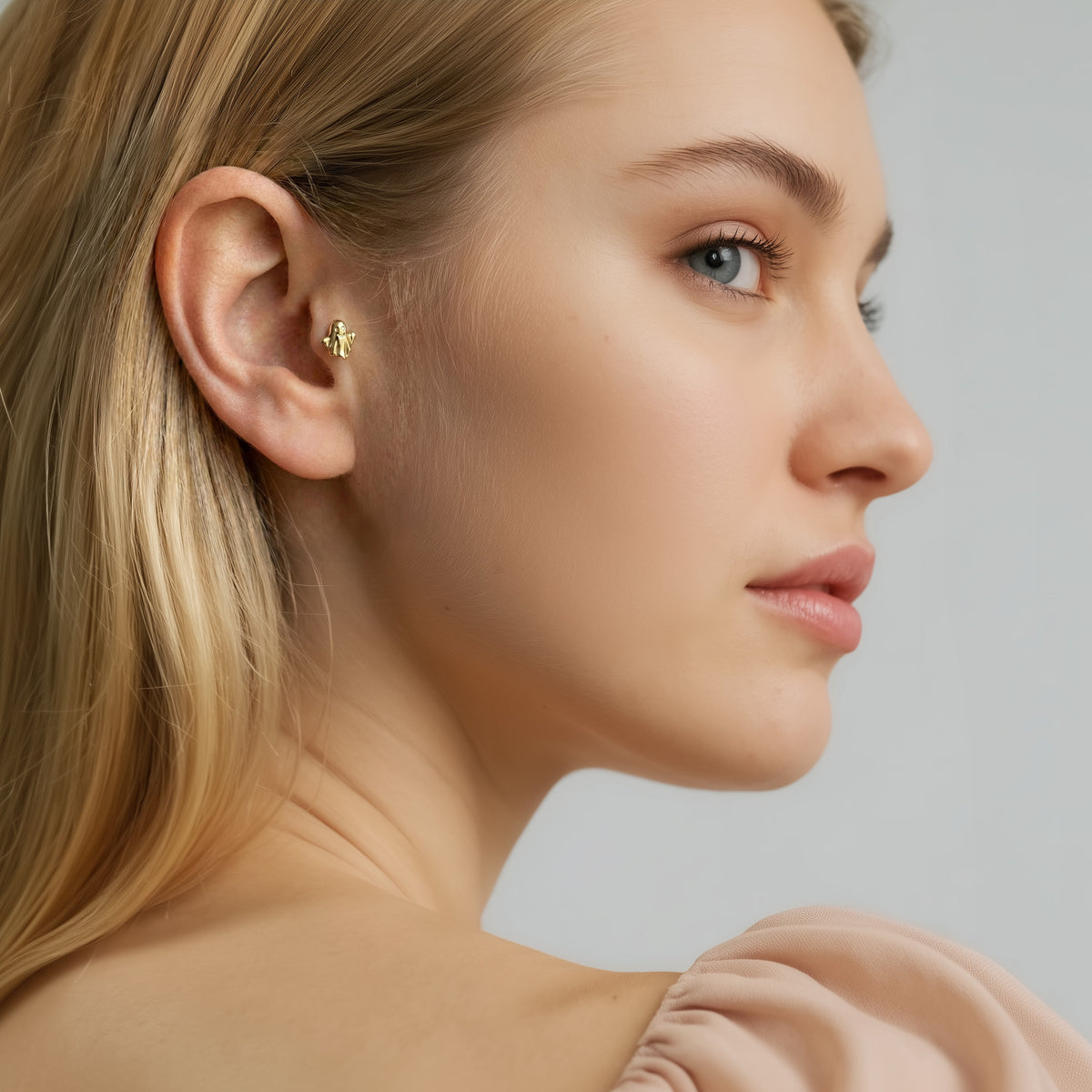 Model wearing the cute ghost ear piercing in a curated cartilage stack for a subtle Halloween accent.
