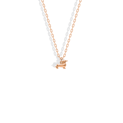 Rose gold warms the dachshund’s elongated outline from muzzle to curled tail