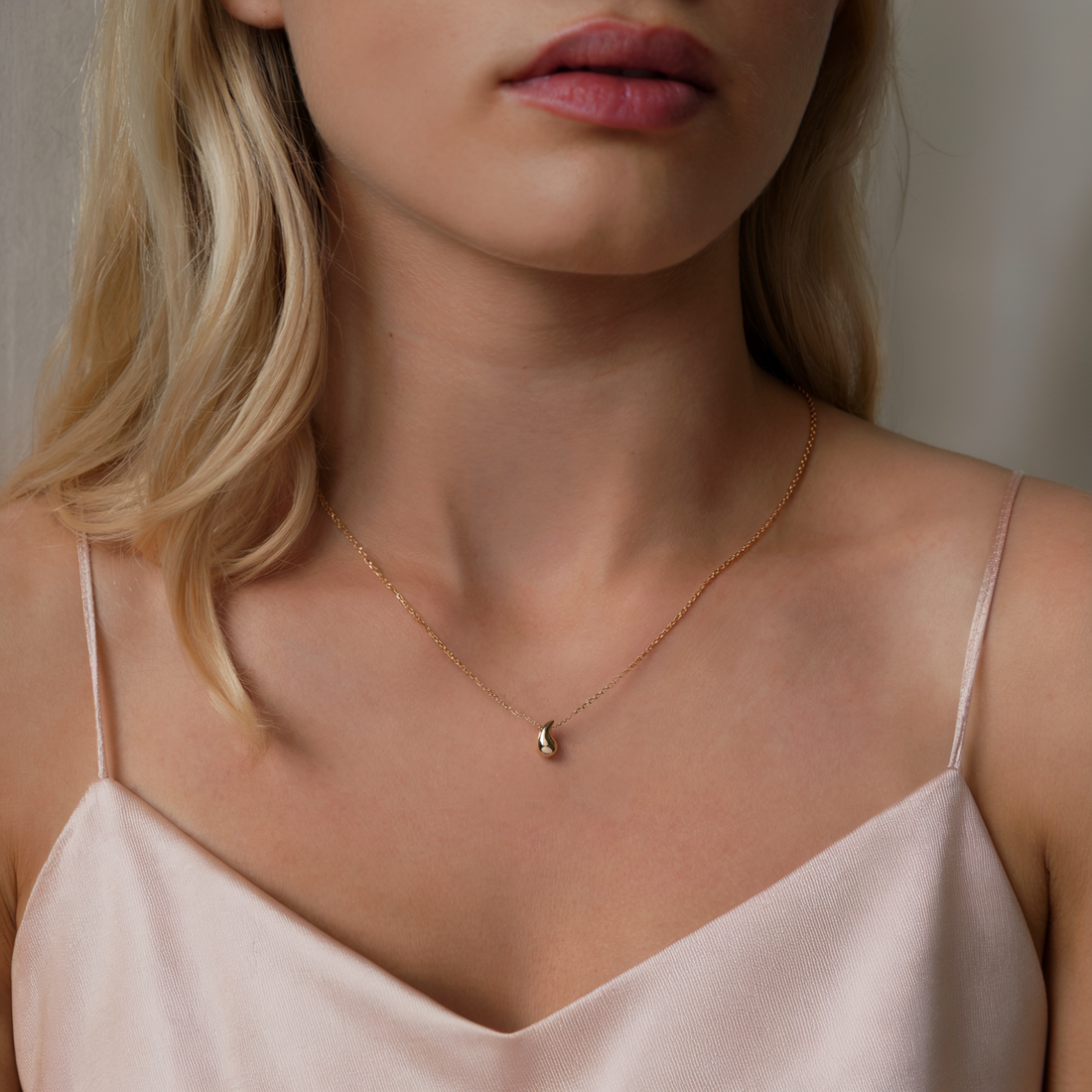 Close-up of a woman wearing a delicate gold necklace with a small pendant.