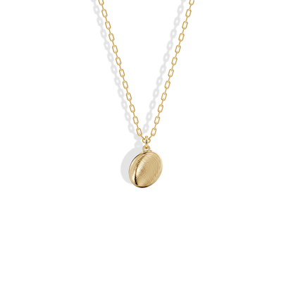 Close studio view of the Fingerprint Oval Custom Necklace 14K Gold / Silver, fingerprint ridges engraved into yellow gold