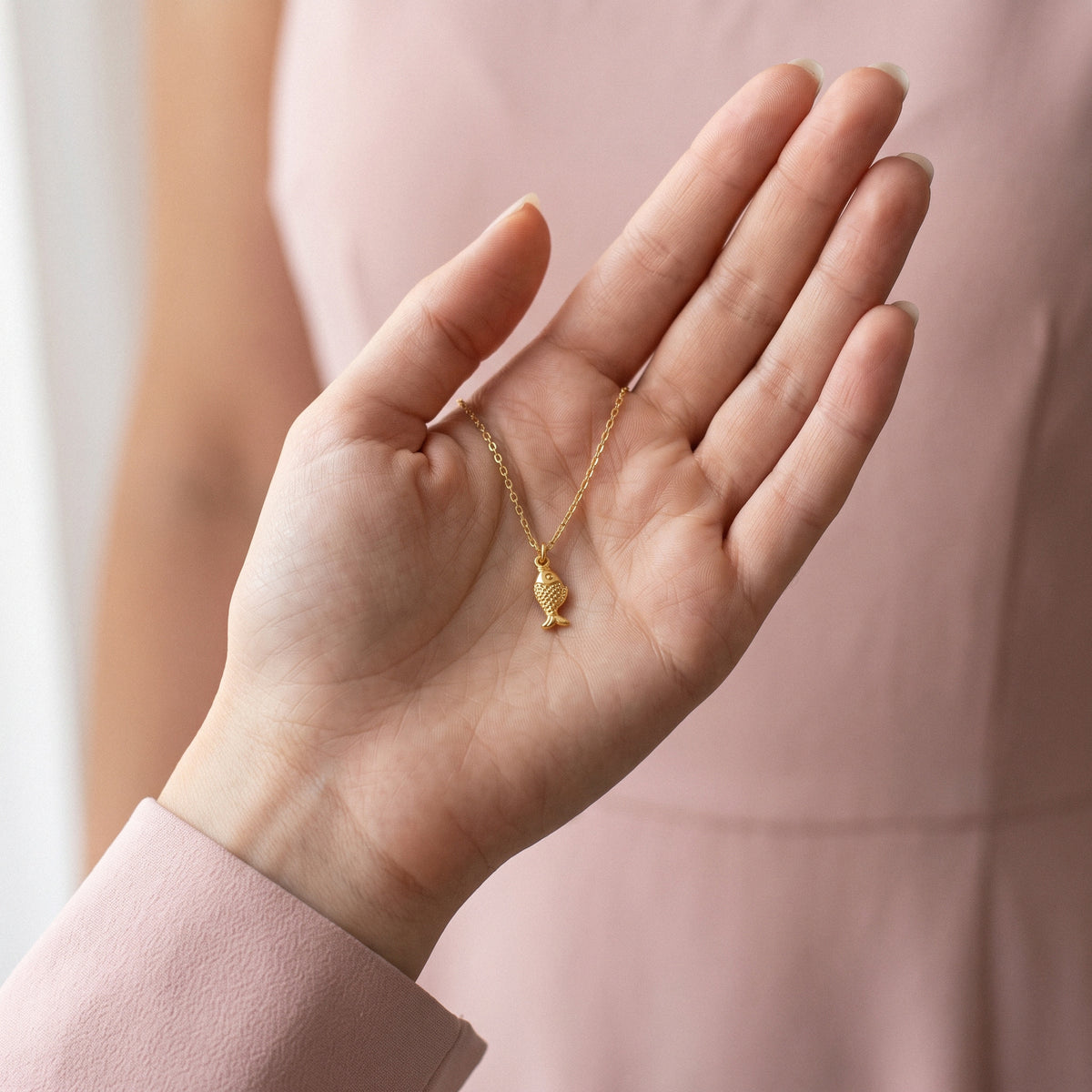 Slim gold fish lying across an open palm, tail pointing towards the wrist