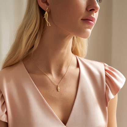 Fish necklace photographed close on a model in a blush satin camisole