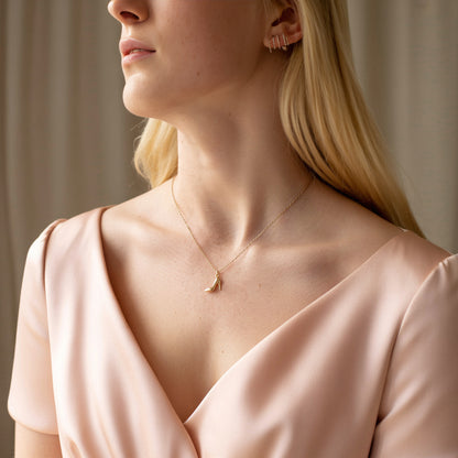 Model in a pink V-neck wearing the gold high heel charm below the throat
