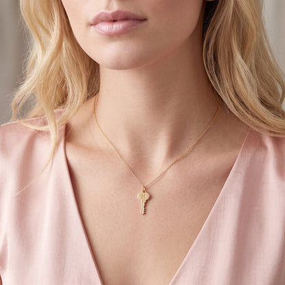 Blonde model in a pink silk blouse wearing the 14K gold key initial necklace