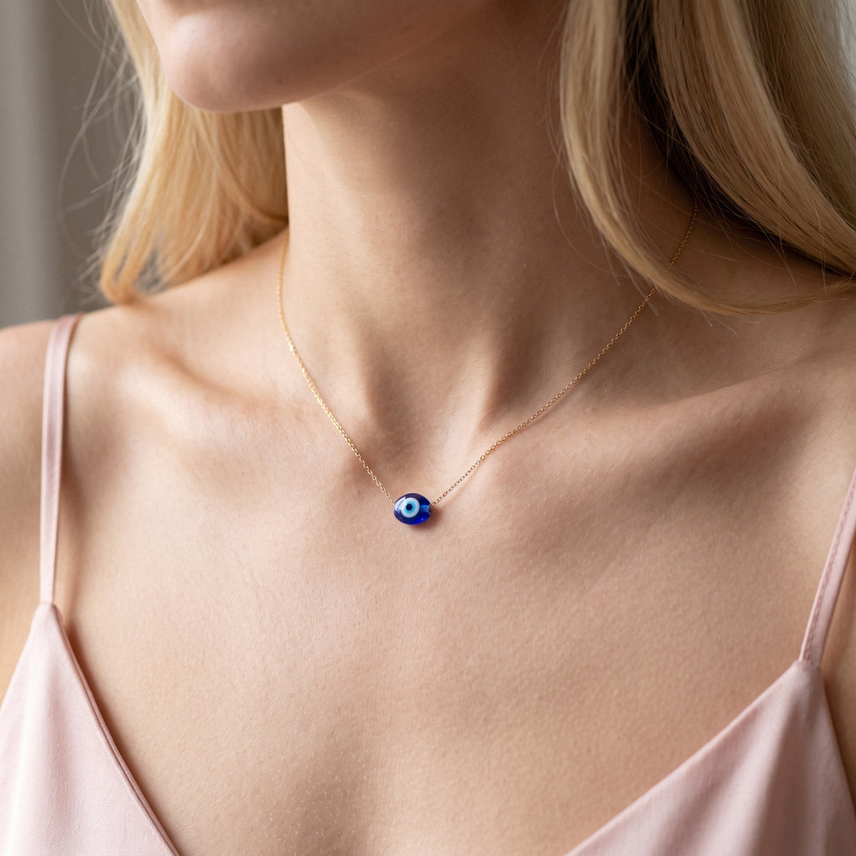Close neckline view showing the rounded protective bead and delicate gold chain