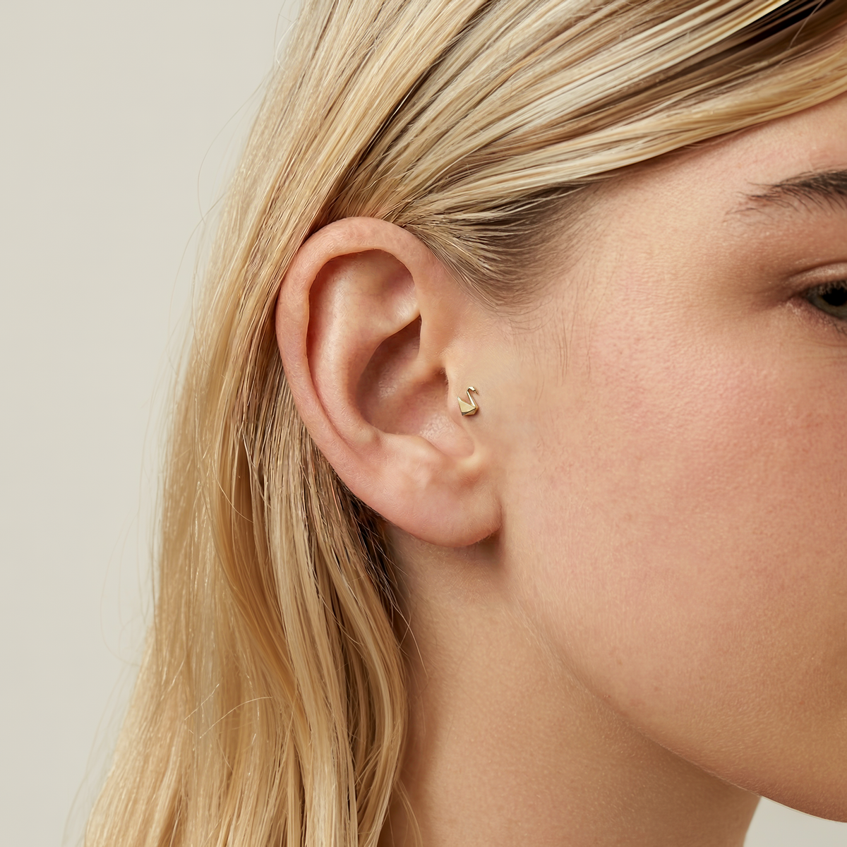 Origami swan flatback ear piercing in solid 14K gold, designed to be worn overnight without removal