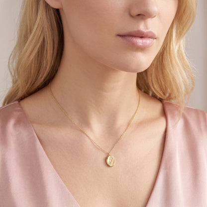 Script name engraving seen close on the gold oval pendant