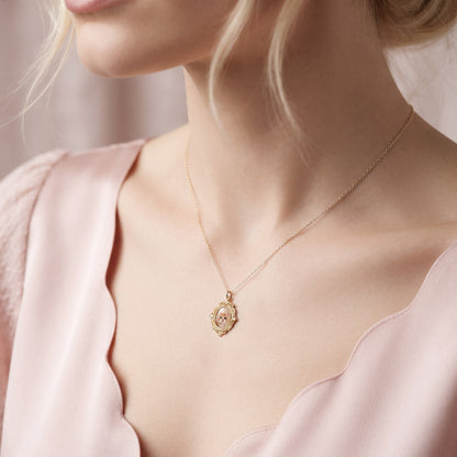 Scalloped pink neckline and an ornate photo locket resting against the collarbone