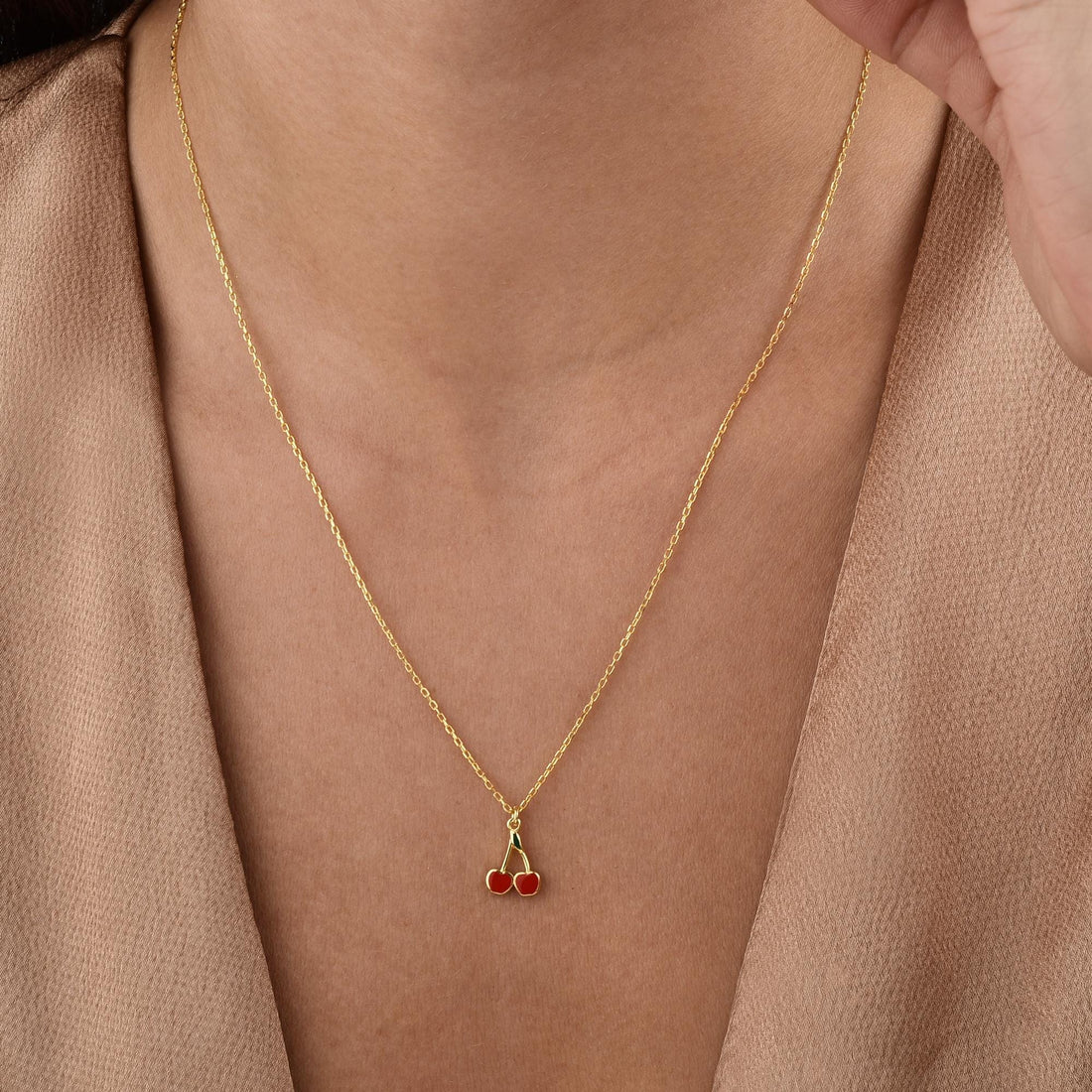 The Red Cherry Design Necklace styled with other gold jewelry, highlighting its playful and elegant design.