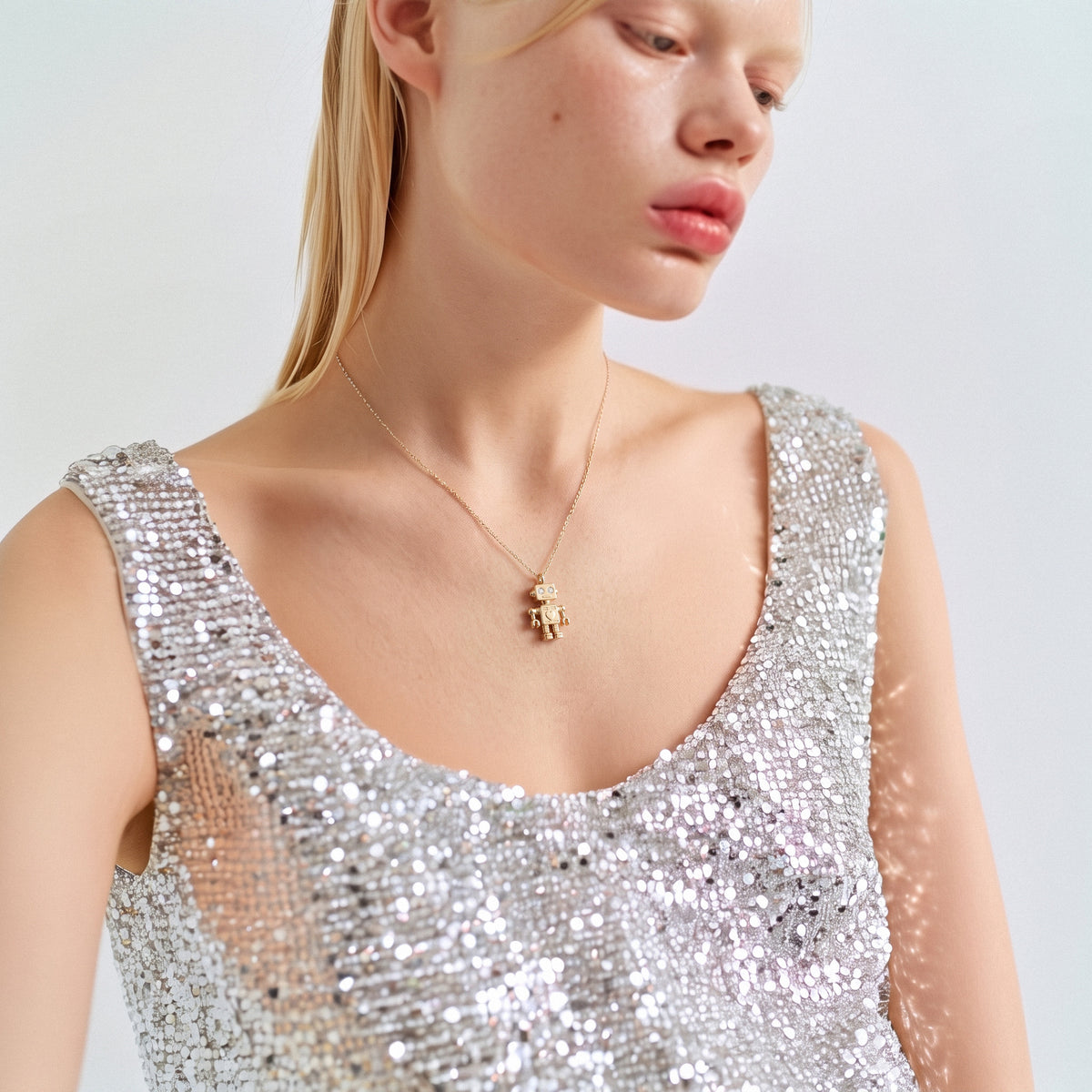 Full view of a model in a sequinned dress wearing the robot pendant necklace