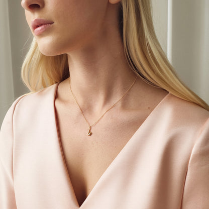 Saxophone charm worn low in the V-neck of a blush wrap blouse