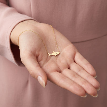 Wide shark pendant lying across an open palm, dorsal fin clearly visible