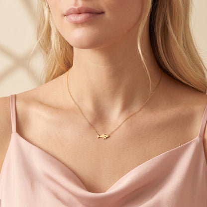 Gold shark necklace shown close against a softly draped pink satin camisole
