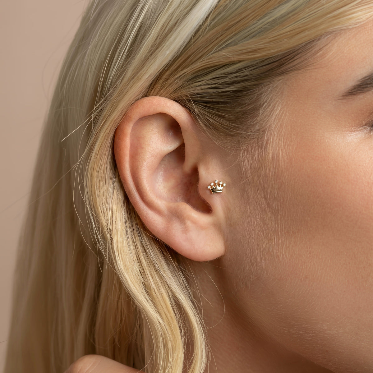 Close ear styling reveals the tiny stone crown and its sparkling row within a polished piercing arrangement.