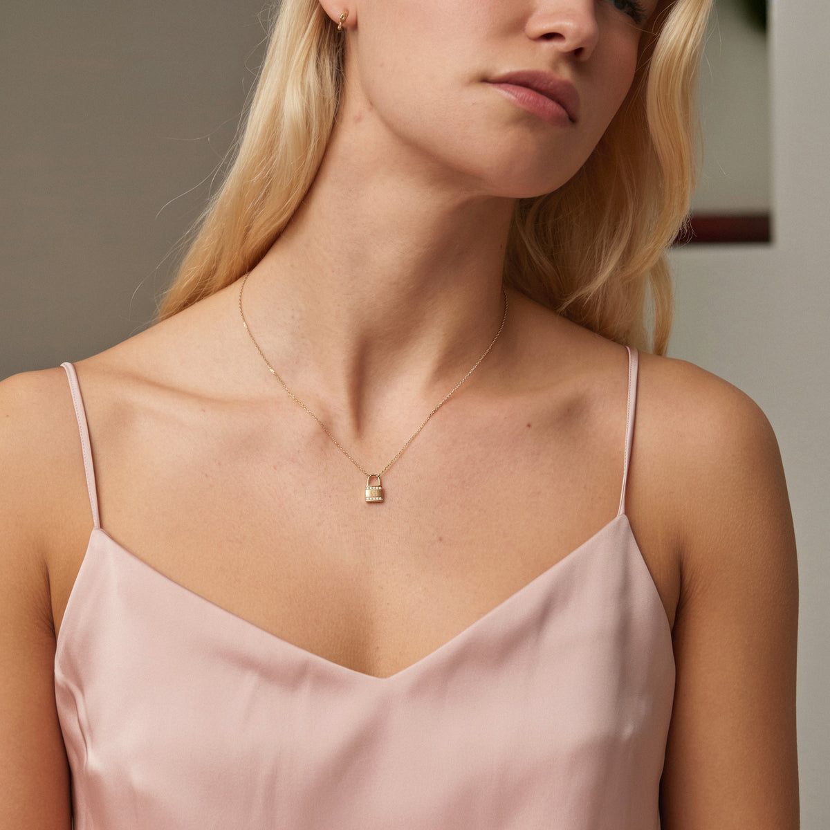 Model in a blush slip dress wearing the diamond padlock initial necklace at collarbone length