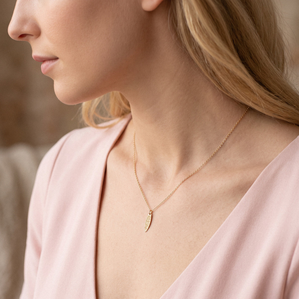 Model in pink wearing the personalised surfboard name necklace at chest height